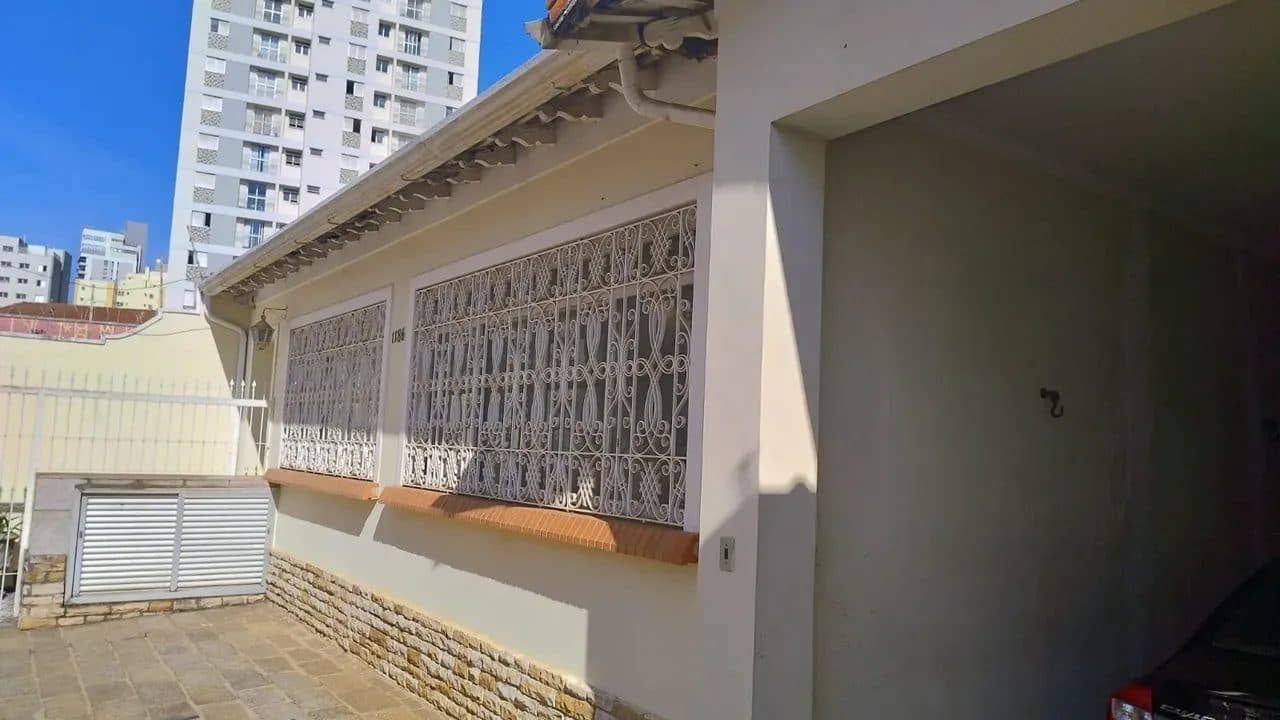 Vista lateral da fachada com detalhes em pedra na base e janelas com grades decorativas.