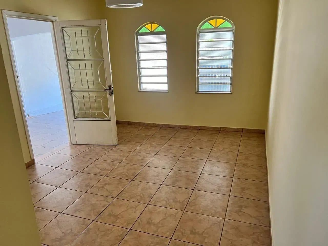 Sala com piso em tom neutro, paredes em tons claros e duas janelas com vidros decorados