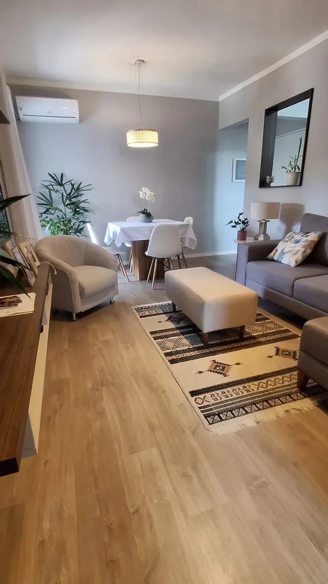 Sala de estar e jantar integrada com piso amadeirado, sofá e mesa de jantar.