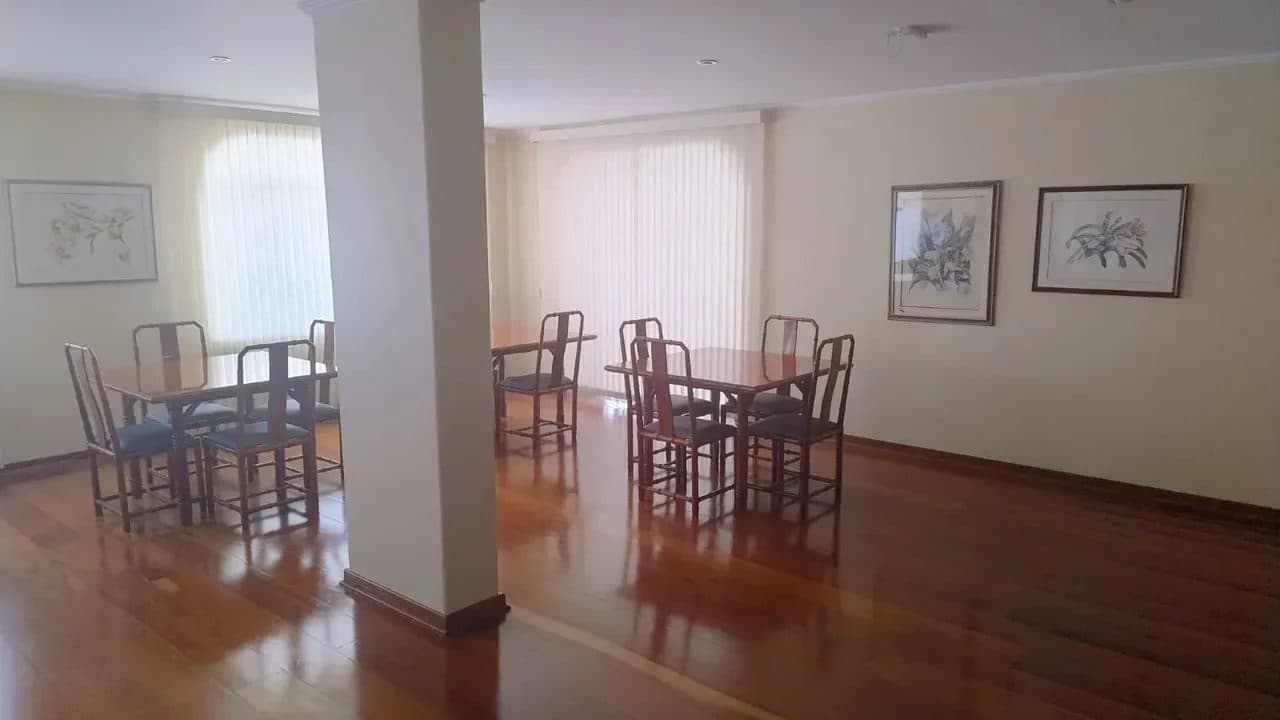 Sala de estar e jantar ampla com piso de madeira e mesas com cadeiras