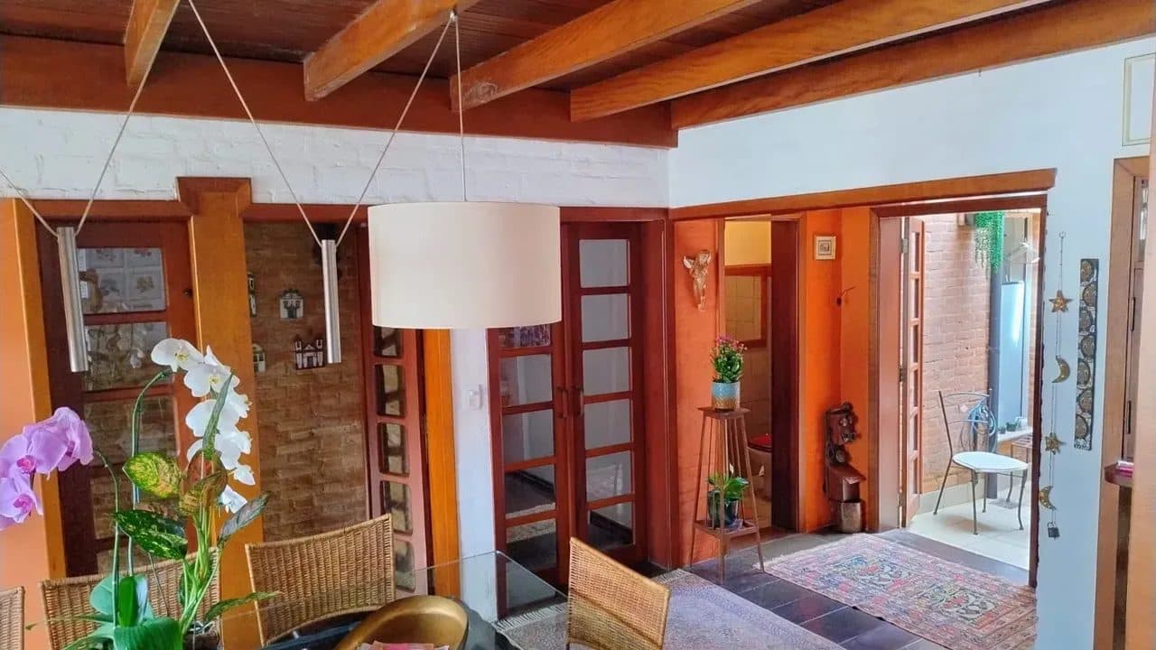 Sala de jantar integrada com mesa de vidro, cadeiras de vime e pendente decorativo.