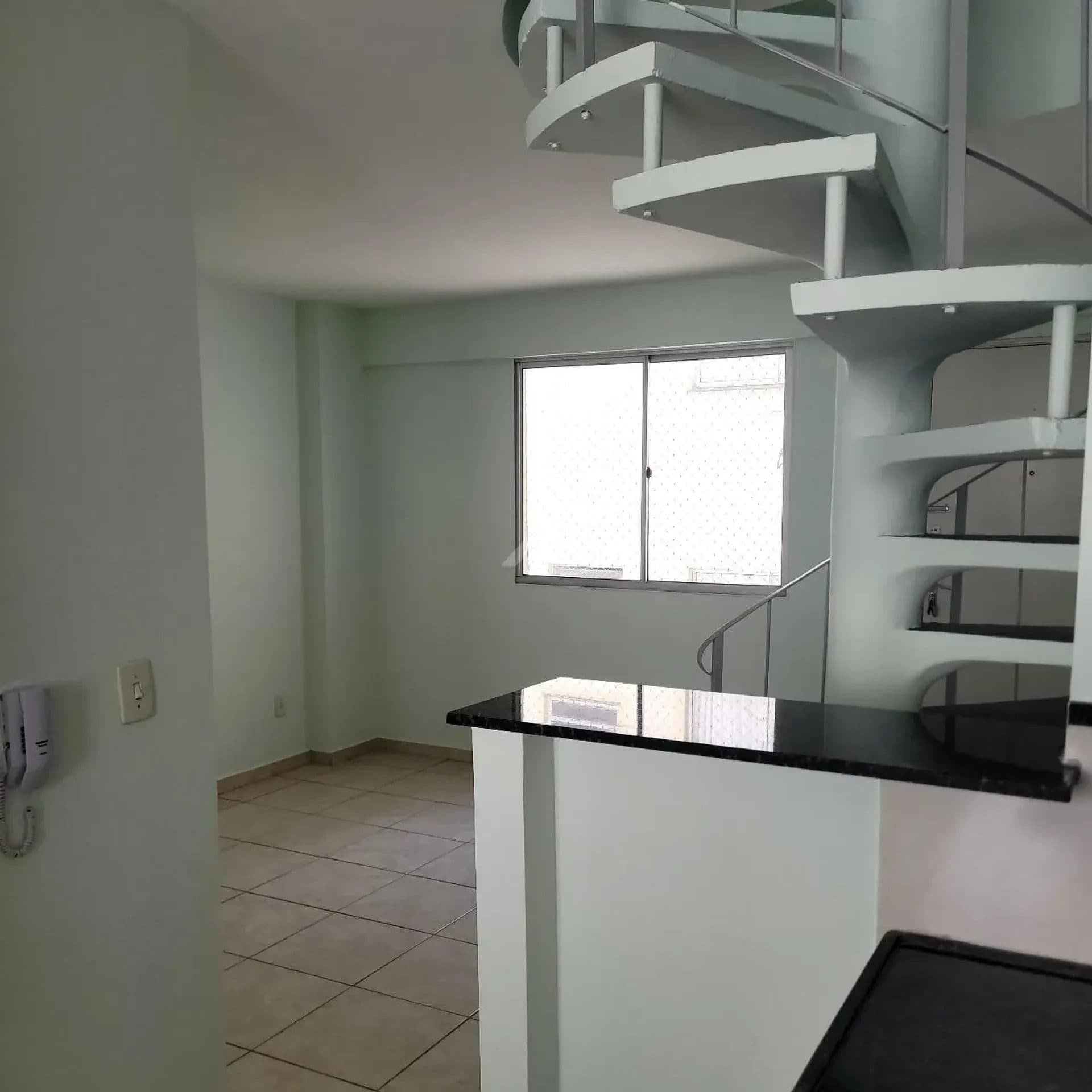 Sala com piso cerâmico, escada caracol e bancada de granito preto.